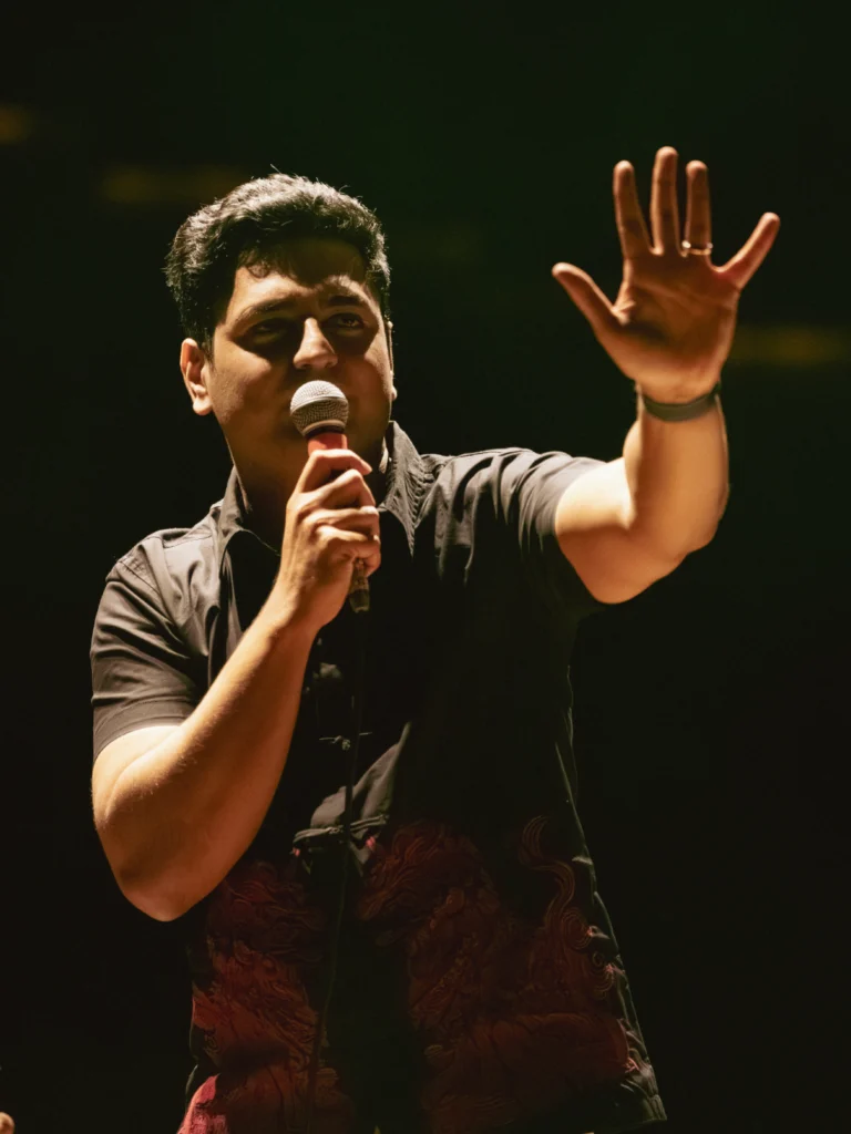 Kenny Sebastian performing live stand-up comedy with a microphone on stage