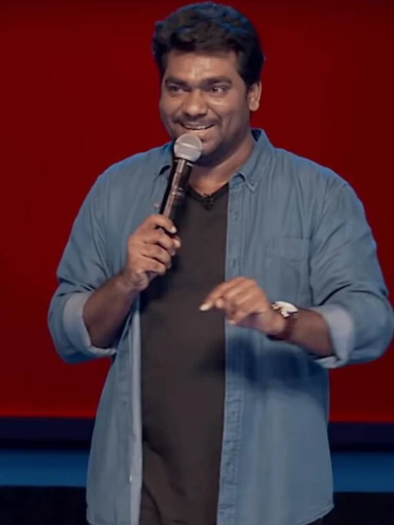 Zakir Khan performing stand-up comedy under stage lights
