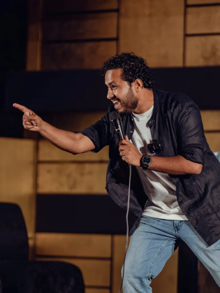 Abish Mathew performing musical stand-up comedy with a microphone.