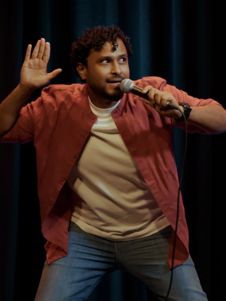 Abish Mathew performing stand-up comedy during a live show.