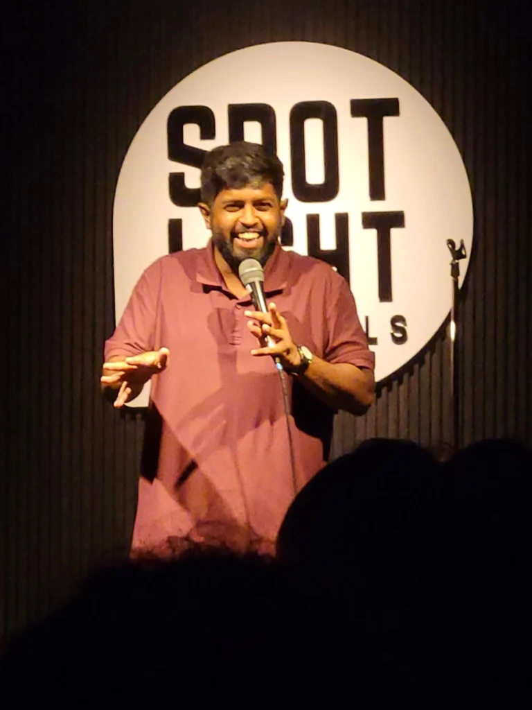 Anand Rathnam performing stand-up comedy at Spotlight Socials in Kochi during a Comedy Lounge show.