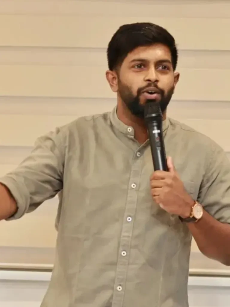 Indian stand-up comedian Anand Rathnam performing live with a microphone.