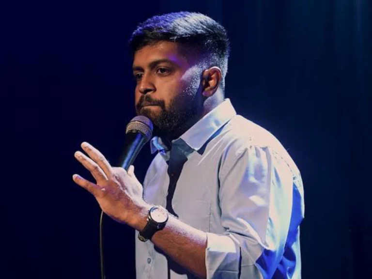 Indian stand-up comedian Anand Rathnam performing live with a microphone.