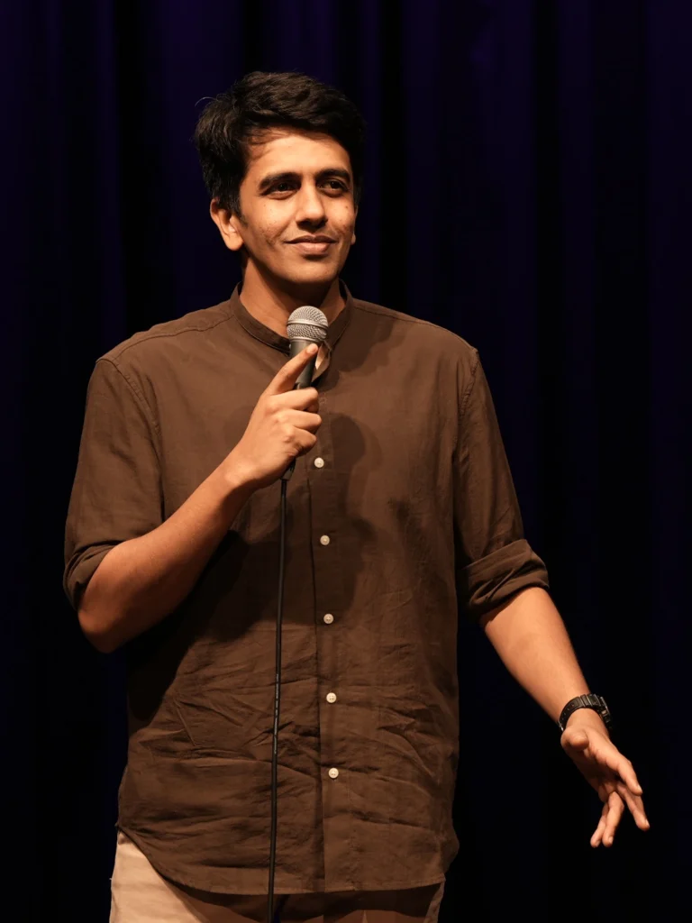 Gautham Govindan performing stand-up comedy during a live comedy show.