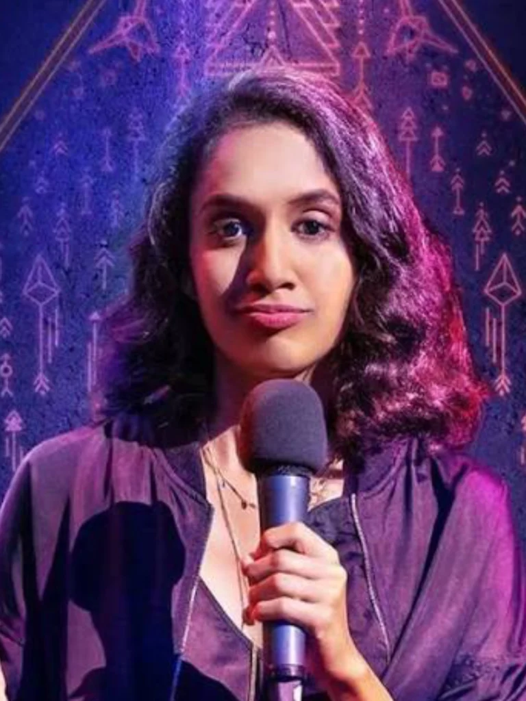 Niveditha Prakasam performing stand-up comedy with a microphone.